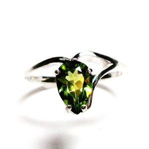 May include: A pear-shaped green gemstone ring set in a silver band with a twisted design.