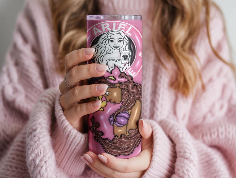May include: A pink tumbler with a mermaid design and the name "ARIEL". The tumbler features a Starbucks-style logo with a mermaid holding a coffee cup. The bottom of the tumbler has a mermaid tail design.