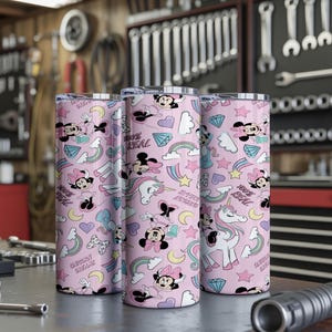 May include: Three pink insulated tumblers with a repeating pattern of Minnie Mouse, unicorns, rainbows, and diamonds. The text "100% REAL" and "UNICORN DREAM" are also featured. The tumblers are cylindrical and appear to be made of stainless steel.