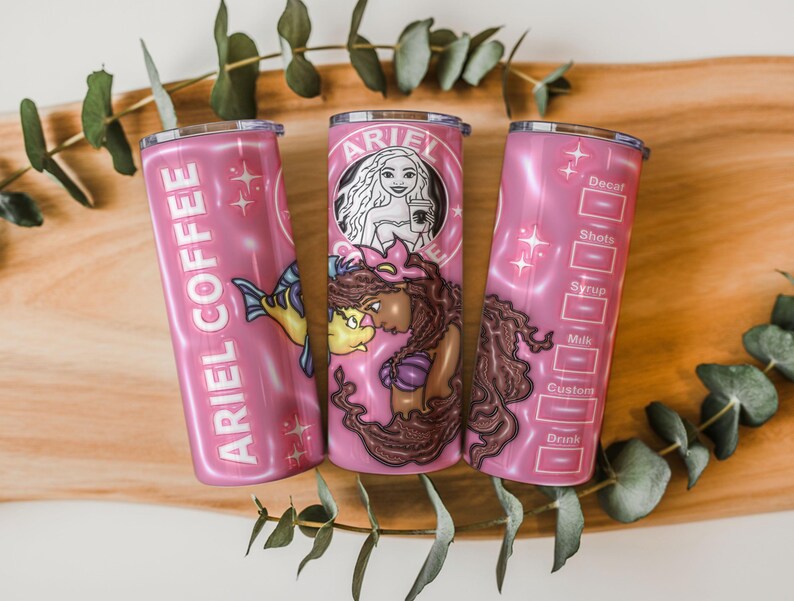 May include: Three pink insulated tumblers with the text "ARIEL COFFEE" and a mermaid graphic. One tumbler features a mermaid with a coffee cup, another has a fish, and the third has drink customization options.