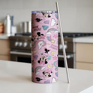 May include: A pink tumbler with a repeating pattern of Minnie Mouse, unicorns, rainbows, and hearts. The tumbler has a silver straw and the text "100% REAL" and "SWEET LEGEND".