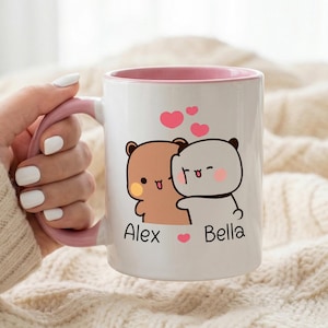 May include: White ceramic mug with a pink interior and handle. The mug features a cartoon illustration of two hugging bears with the names "Alex" and "Bella" below. Pink hearts float above the bears.