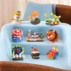 May include: A collection of colorful clay figurines, including a mushroom, a lion, a cake, and a miniature living room scene. The figurines are arranged on a light blue surface, showcasing various shapes and designs. The overall theme is whimsical and playful.