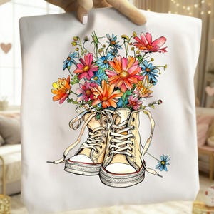 Könnte beinhalten: Weiße Tragetasche mit floralem Design. Das Kunstwerk zeigt einen Strauß bunter Blumen in einem Paar cremefarbener High-Top-Sneaker. Die Blumen sind in Rosa-, Orange-, Blau- und Gelbtönen gehalten.