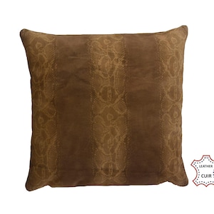 Könnte beinhalten: Ein quadratisches, braunes Lederkissen mit einem Muster. Das Kissen hat vertikale Bahnen mit einem helleren, strukturierten Muster. Das Leder hat einen warmen, erdigen Ton und das Kissen hat ein weiches, einladendes Aussehen. Ein dekoratives Wohnaccessoire.