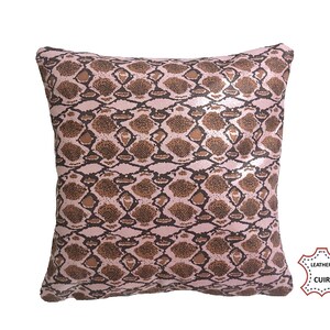 Peut inclure: Coussin carré décoratif avec un motif peau de serpent dans les tons marron et rose. Le coussin a une texture cuir et est probablement en simili cuir. Un article de décoration intérieure.