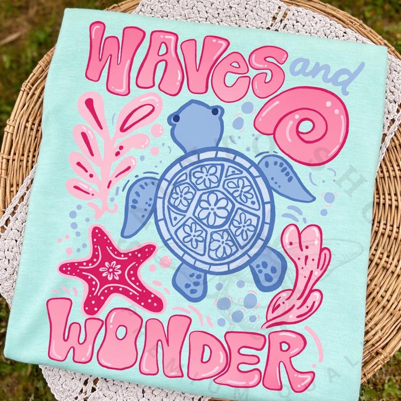 Pu&ograve; includere: T-shirt azzurra con le parole "WAVES and WONDER" in lettere rosa a bolle. La maglietta presenta una tartaruga blu, una stella marina rosa e altre grafiche a tema marino.