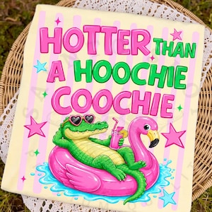 May include: A light yellow t-shirt with the text "HOTTER THAN A HOOCHIE COOCHIE" in pink and green. The graphic features an alligator wearing heart-shaped sunglasses, relaxing on a pink flamingo float, holding a drink. Pink stars and blue water complete the design.