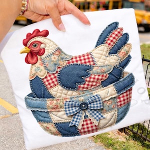 Könnte beinhalten: Ein weißes Kissen mit einem Patchwork-Hühnerdesign. Das Huhn besteht aus Denim, Blumenmustern und rot-weiß karierten Stoffen. Eine blau-weiß karierte Schleife mit Knopf und Spitzendetails ziert den Boden. Das Huhn sitzt in einem Patchwork-Korb.