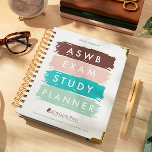 Op de afbeelding: Een spiraalgebonden planner met de woorden "ASWB EXAM STUDY PLANNER" in een kleurrijk ontwerp. Een bril met schildpadmotief, een witte headset en een pen liggen ook op het houten oppervlak. Een kleine klok en een plant staan op de achtergrond.