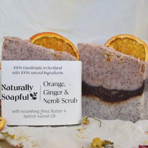 Può includere: Sapone Naturally Soapful Orange, Ginger & Neroli Scrub. Il sapone è di colore marrone chiaro con uno strato marrone scuro e sormontato da una fetta d'arancia. L'etichetta recita: "100% Fatto a mano in Scozia con ingredienti naturali al 100%."