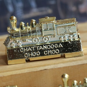 May include: Gold-colored metal train engine souvenir with the words "Chattanooga Choo Choo" on the bottom.