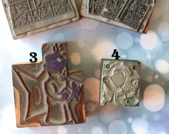 May include: Four vintage wooden printing blocks with raised designs. The blocks are numbered 1 through 4. Block 1 has a winter scene with houses, trees, and a snowman. Block 2 has a winter scene with a house, trees, and a bird. Block 3 has a snowman holding a bird. Block 4 has a snowman holding a bird.