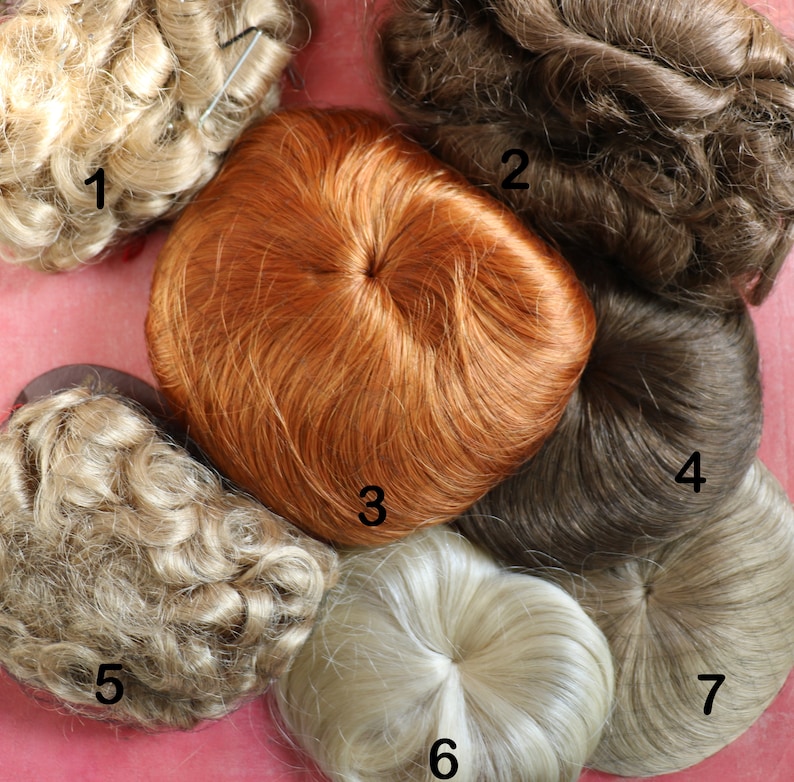 May include: Seven different hairpieces in various colors and styles. The hairpieces are arranged in a circle on a pink surface. The hairpieces are numbered 1 through 7.