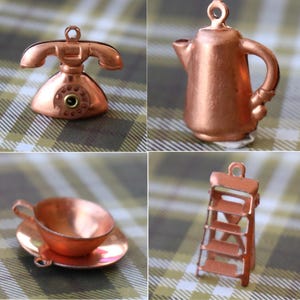 May include: Four miniature copper-colored charms: a vintage telephone, a teapot, a teacup and saucer, and a small ladder. The charms are detailed and have a metallic finish, perfect for jewelry making or crafting projects.
