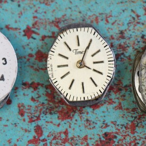 May include: Five vintage watch faces with different styles and designs. The watch faces are all white with black numbers and hands. Some of the watch faces have a gold trim.