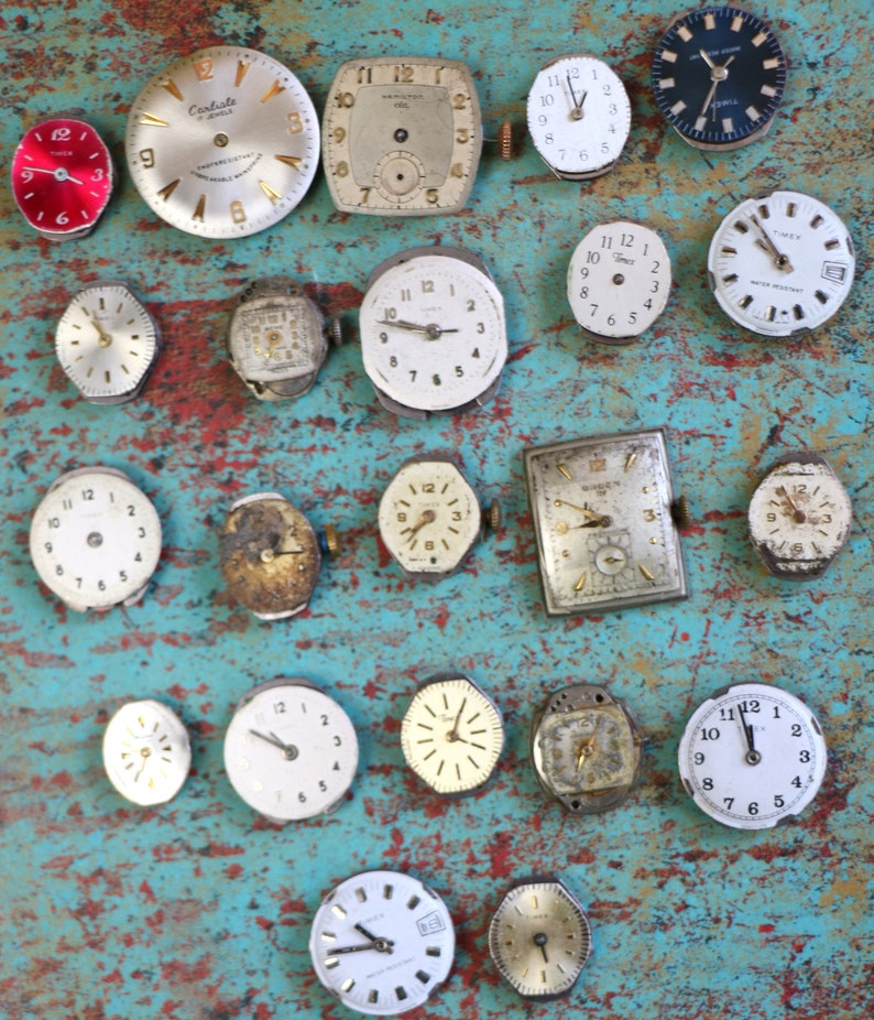 May include: A collection of vintage wristwatches in various styles and colours, including silver, gold, and black. Some watches have Roman numeral markings, while others have Arabic numerals. The watches are arranged on a blue and green textured surface.