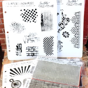 May include: A set of clear rubber stamps with black ink designs. The stamps feature various patterns, including polka dots, checkered, brick, and floral designs. The stamps are labeled "Stampers Anonymous" and "Jim Holtz Collection".