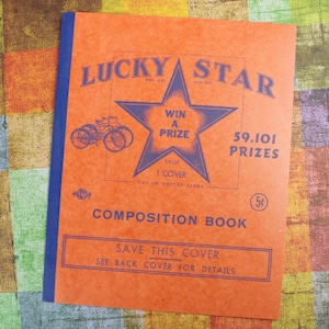 May include: An orange composition book cover with a blue star and bicycle graphic. The cover says "Lucky Star" and "Win a Prize". It also says "59,101 Prizes" and "Value 1 Cover".