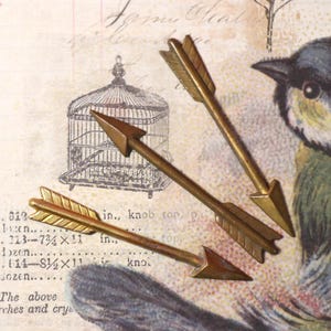 May include: Three antique brass arrows with feathered fletching, arranged on a vintage paper background with a bird illustration and text. The arrows are approximately 3 inches long.