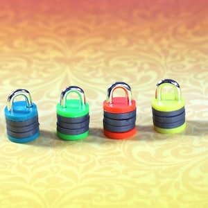 May include: Four small padlocks in different colors: blue, green, red, and yellow. Each padlock has a silver metal loop and a black band around the middle.