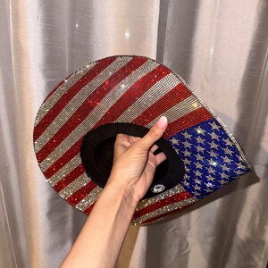K&ouml;nnte beinhalten: Ein Hut mit amerikanischer Flaggenmusterung in Rot, Wei&szlig; und Blau, der mit Strasssteinen besetzt ist.