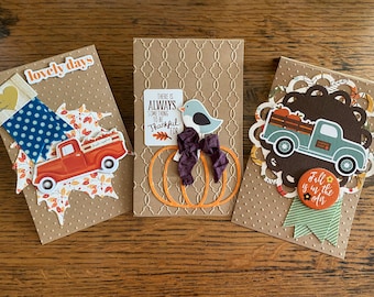 May include: Three handmade cards with fall themes. The first card features a red truck with a fall leaf design and the text "lovely days". The second card features a bird and pumpkins with the text "There is always something to be thankful for". The third card features a blue truck with pumpkins and the text "Fall is in the air".