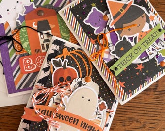 May include: Three handmade Halloween greeting cards featuring layered paper cutouts of ghosts, pumpkins, a witch, and a haunted house. The cards include decorative elements like twine bows, stars, and text reading "BOO", "TRICK OR TREAT!", and "Halloween night".