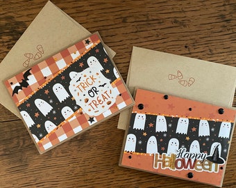 May include: Two handmade Halloween greeting cards with a ghost theme. One card has a black and white checkered background with ghosts and the text "Trick or Treat". The other card has an orange and black background with ghosts and the text "Happy Halloween".