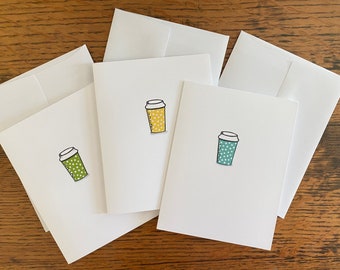May include: Four blank white cards with different colored coffee cup illustrations. The cups are green, yellow, and blue with white polka dots.
