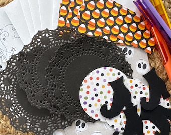 May include: A collection of craft supplies including white envelopes, black paper doilies, circular paper cutouts with colorful polka dots, rectangular paper strips with a candy corn pattern, skull-patterned paper, black witch boot cutouts, and three pens.