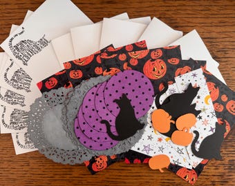 May include: A collection of Halloween-themed paper craft supplies including white cards with black text, black paper cat silhouettes, purple polka-dot circles, orange pumpkin cutouts, gray lace-patterned paper doilies, and patterned paper sheets.