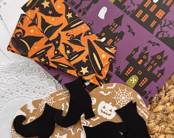 May include: A collection of Halloween-themed paper craft supplies including rectangular cards with orange witch hat patterns, purple cards featuring haunted house illustrations, circular tan coasters with white pumpkin and spiderweb prints, and black witch boot cutouts.