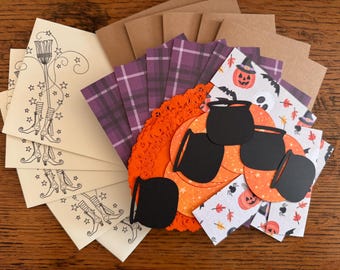 May include: A collection of Halloween-themed craft supplies. Includes cream-colored cards with witch boot illustrations, purple plaid paper, orange doilies, black cauldron cutouts, and patterned paper with pumpkins and bats.