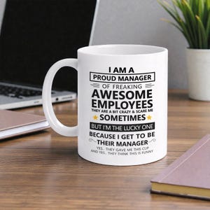 Puede incluir: Taza de cerámica blanca con el texto "I AM A PROUD MANAGER OF FREAKING AWESOME EMPLOYEES" en negro. La taza también incluye las frases "THEY ARE A BIT CRAZY & SCARE ME SOMETIMES" y "BUT I'M THE LUCKY ONE BECAUSE I GET TO BE THEIR MANAGER."