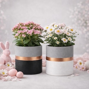 Könnte beinhalten: Ein Set aus drei Keramikbechern mit gesprenkelter, matter Oberfläche. Die Becher sind in Creme-, Hellgrau- und Dunkelgrautönen gehalten. Jeder Becher hat ein schlichtes, minimalistisches Design.