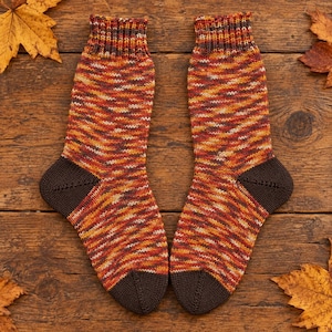 Puede incluir: Un par de calcetines de punto a media pantorrilla con un patrón de hilo jaspeado en tonos naranja, amarillo, rojo y marrón. Los calcetines tienen talones, punteras y puños acanalados en marrón oscuro sólido, con una textura detallada.