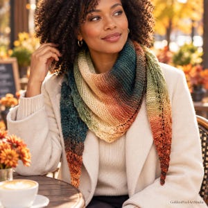 May include: A triangular knitted shawl featuring a gradient colour pattern that transitions from deep teal and forest green to warm orange, yellow, and cream tones. The accessory has a textured stitch pattern with delicate lace-like eyelet details.