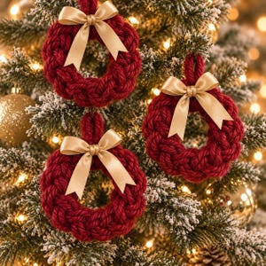 May include: Three circular ornaments crafted from thick, braided dark red yarn. Each wreath-shaped decoration features a smooth, light gold satin ribbon tied into a bow at the top, with two hanging tails extending downward over the textured yarn.