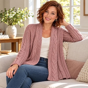 Peut inclure: Un cardigan ouvert rose poudré présentant une texture en tricot épais avec des détails de torsades verticales sur les panneaux avant et les manches. Le vêtement est porté sur un haut blanc uni et un jean bleu, offrant une coupe décontractée.