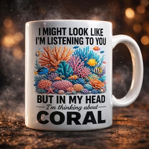 May include: White ceramic mug with a handle, featuring a colorful coral reef design with fish. The mug has the text "I MIGHT LOOK LIKE I'M LISTENING TO YOU BUT IN MY HEAD - I'm thinking about - CORAL".
