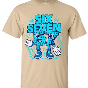 May include: A tan t-shirt featuring a cartoon graphic of the words "SIX SEVEN" in blue, with the numbers designed as a character with arms, legs, and a smiling face. The design includes lightning bolt accents.