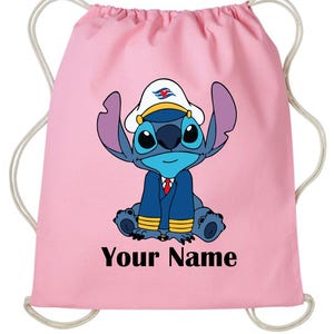 Op de afbeelding: Roze trekkoordtas met een blauw stripfiguur met een witte kapiteinshoed en een marineblauwe jas. De tekst "Your Name" is in het zwart onderaan gedrukt. De tas heeft witte trekkoorden.
