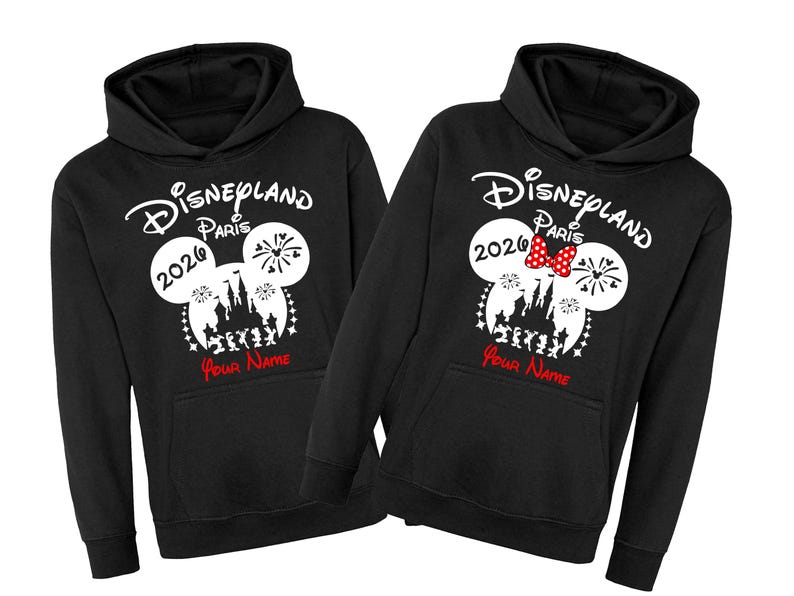Może przedstawiać: Czarne bluzy z kapturem z logo Disneyland Paris, uszami Myszki Miki i rokiem 2020. Jedna bluza ma czerwoną kokardę. Tekst "Your Name" jest wydrukowany na czerwono pod projektem.