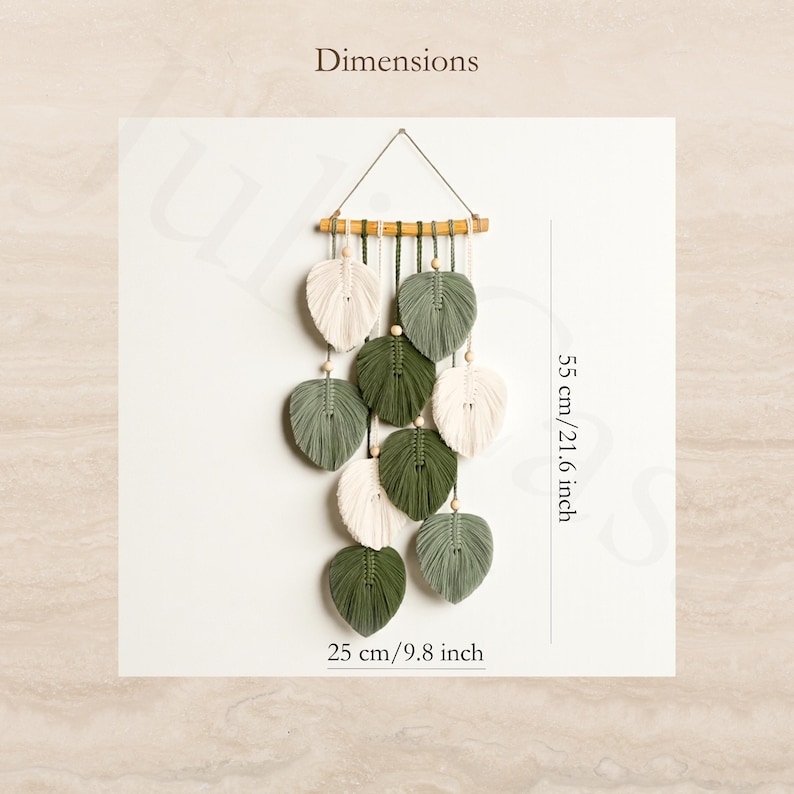 Puede incluir: Colgante de pared de macram&eacute; con dise&ntilde;os en forma de hojas en blanco y verde, suspendido de una clavija de madera. Las dimensiones son 55 cm de altura y 25 cm de ancho. El texto "Dimensions" est&aacute; en la parte superior.