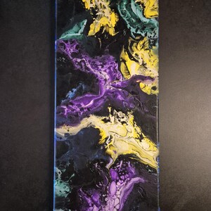 Op de afbeelding: Abstract acrylverfschilderij op canvas. Het kunstwerk heeft een donkere achtergrond met wervelende patronen van geel, paars, blauwgroen en blauw. De kleuren vloeien in elkaar over en contrasteren, waardoor een dynamisch en gestructureerd visueel effect ontstaat. Het canvas is rechthoekig.