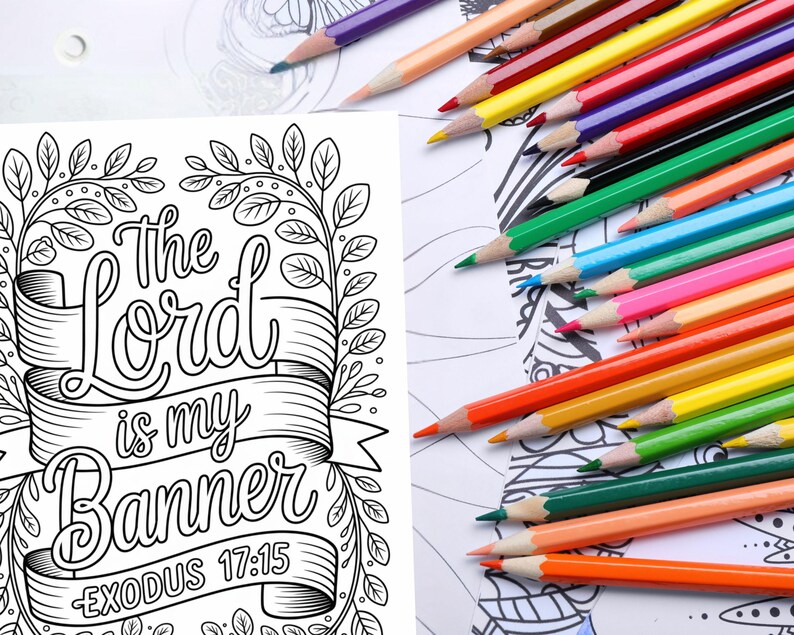 May include: A coloring page with the text "The Lord is my Banner Exodus 17:15" surrounded by a floral design. A collection of colored pencils in various colors are scattered across the page, ready for use.