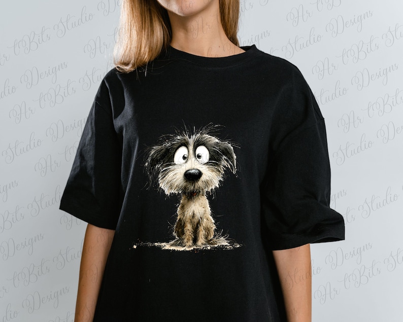 May include: Black t-shirt featuring a cartoon illustration of a dog with big eyes and shaggy fur. The dog is depicted in shades of black, white, and brown. The shirt is a casual style, suitable for everyday wear.