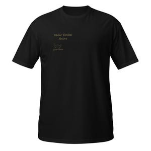May include: Black t-shirt with short sleeves. The shirt displays the text "Divine Timing Always" in gold, accompanied by a logo. The tee is made of a soft material, suitable for casual wear. The shirt is a versatile item.
