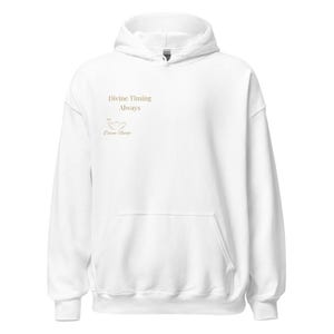 May include: A white hoodie with a front pocket and a drawstring. The words "Divine Timing Always" are printed in gold on the front, along with a small graphic and the words "Divine Nudge".